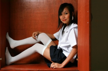 Cute Asian student showcases her bald cunt on a shelf in white OTK socks