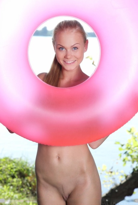 Naked blonde teen Nancy A poses by herself on a pink inner tube by the water - pornpics.de