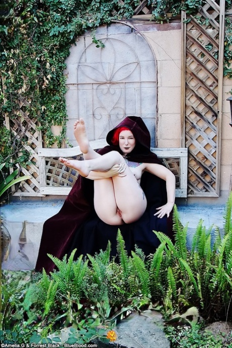 Tattooed redhead Zelda wears a cape while showing her naked body in a garden - pornpics.de