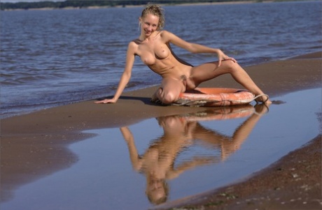 Naked blonde tosses a life preserver in the sea while hanging at the beach - pornpics.de