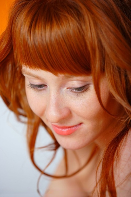 Natural redhead Ossana cups a natural breast while taking off her dress