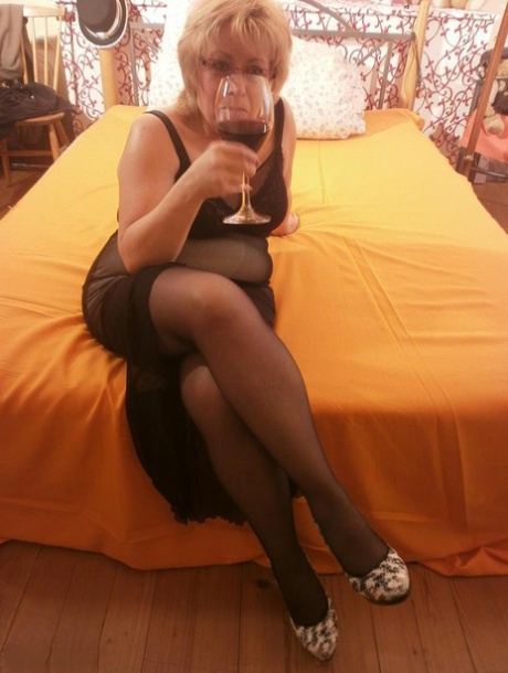 Tipsy hot granny Caro spreading legs on the bed wearing black stockings