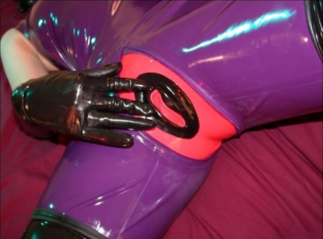 Solo model inserts a dildo while wearing head to toe latex clothing