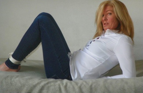 Blonde woman is cleave gagged and hogtied in a white blouse and blue jeans