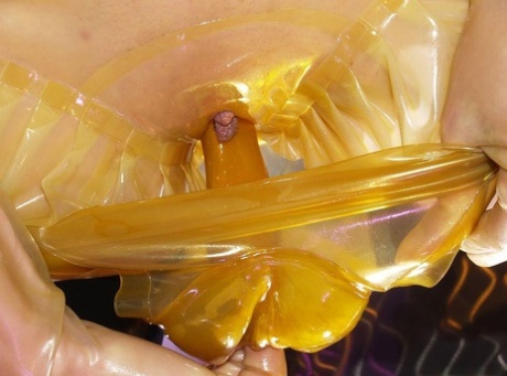 Kinky chick in latex clothing and a mask slides a dildo up her cameltoe pussy