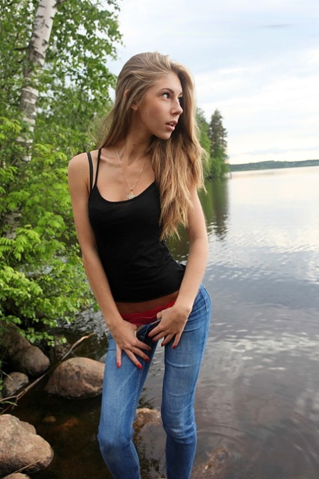 Girl next door Megan pulls out her tits while sitting on a rock in the lake - pornpics.de