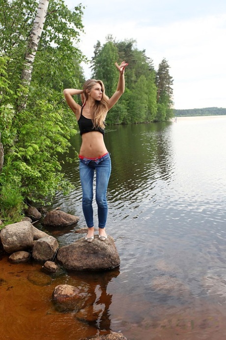 Girl next door Megan pulls out her tits while sitting on a rock in the lake - pornpics.de