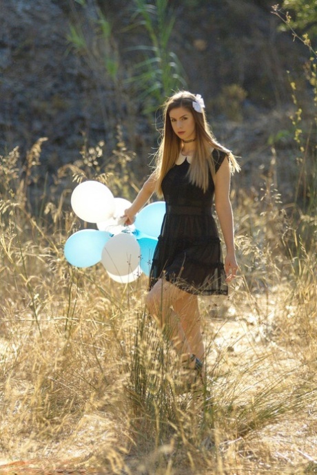 Beautiful girl Stella Cox holds a bunch of balloons after getting nude outside
