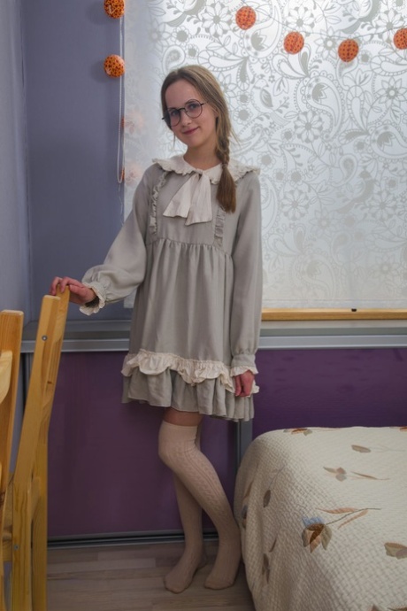 Nerdy girl takes off her dress and pretties along with her glasses on her bed - pornpics.de
