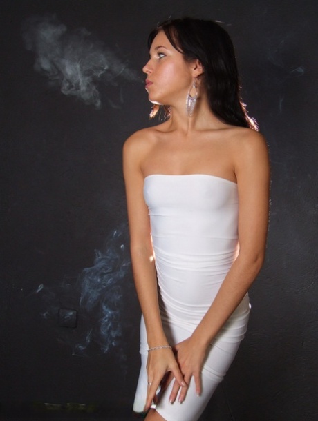 Young brunette smokes a cigarette while wrapped in tight white dress and heels - pornpics.de