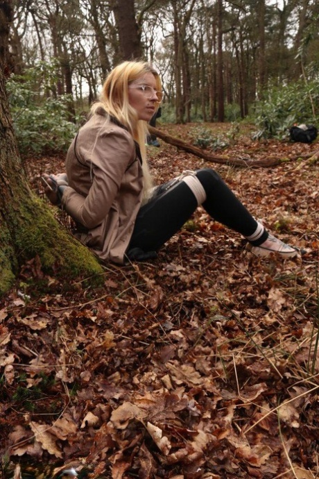 Glasses wearing woman in tied with ropes to a treed in woods with clothes on