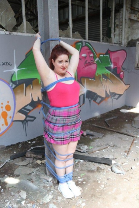 Chubby redhead is fitted with a ball gag and tied to a post and that