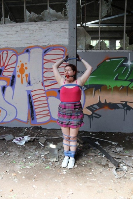Chubby redhead is fitted with a ball gag and tied to a post and that