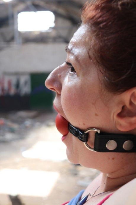 Chubby redhead is fitted with a ball gag and tied to a post and that