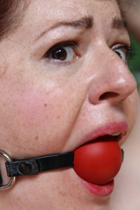 Chubby redhead is fitted with a ball gag and tied to a post and that