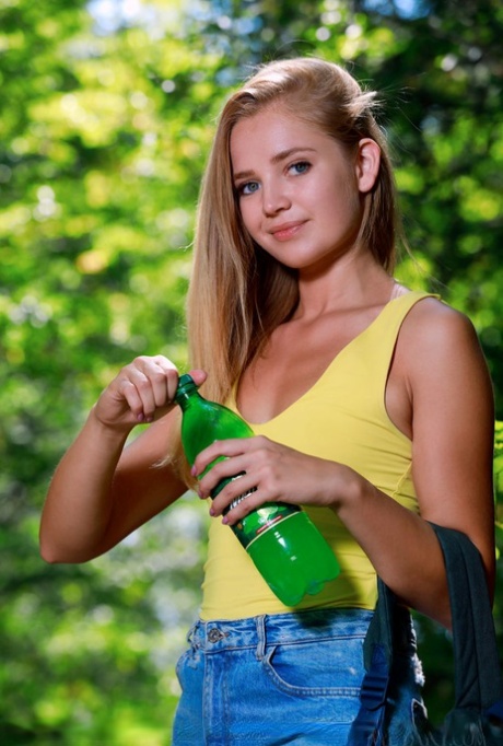 Petite teen Gabriella crosses bare legs before posing nude on a path in woods