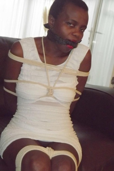 Black female is left tied and cleave gagged in a white dress on a leather sofa - pornpics.de