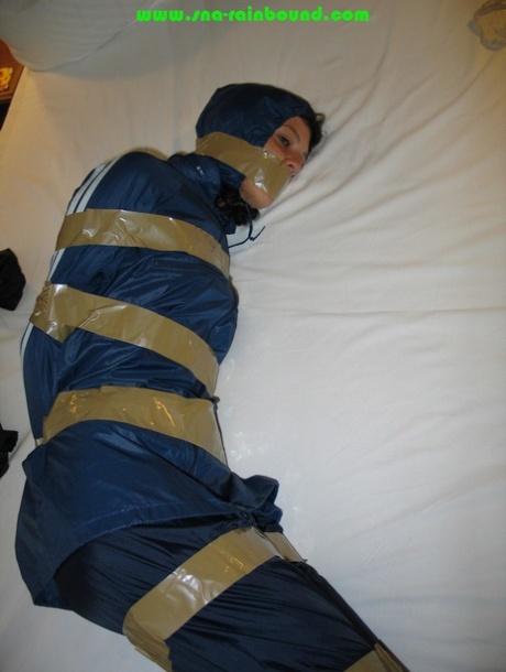 Caucasian female is left tied up and gagged while wearing nylon rain wear