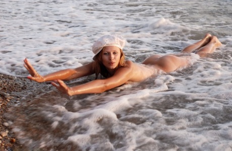 Naked teen Flower takes off her hat while frolicking in ocean surf - pornpics.de