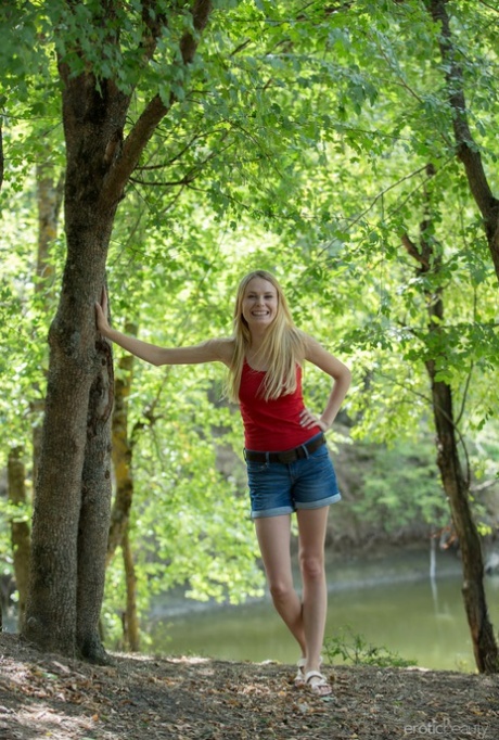 Young blonde Maria Rubio showcases her bald twat on a stump by a river