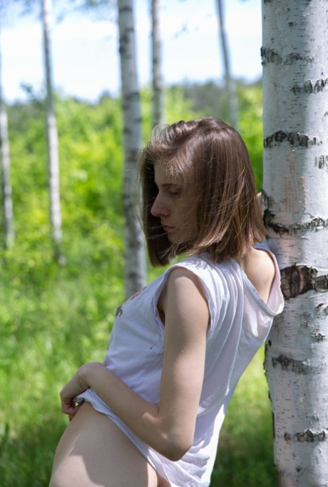 Skinny 18-year-old Anna R grabs her tight ass and snatch against a birch tree