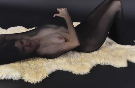 Naked mature woman encases herself in a stocking atop a rug - pornpics.de