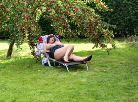 Plump amateur Roxy displays her huge boobs and bald cunt under a fruit tree - pornpics.de