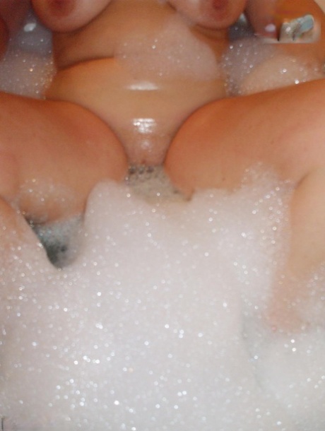 Older amateur Busty Bliss licks her lips during a playful bubble bath - pornpics.de