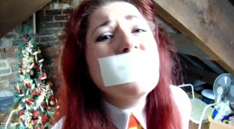 Overweight redhead Mada Rose is bound with rope while struggling against a gag