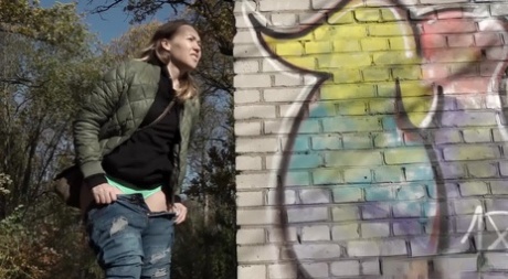 Short taken girl pulls down her jeans to take a piss by a brick building - pornpics.de