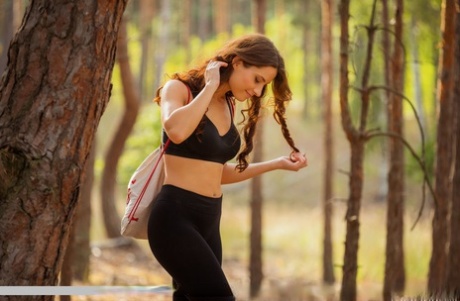 Sweet teen Mara Blake removes spandex attire on a yoga mat in a forest