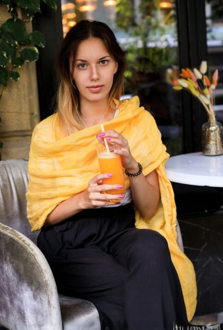 Teen model Giselle sips orange juice outdoors before getting naked indoors