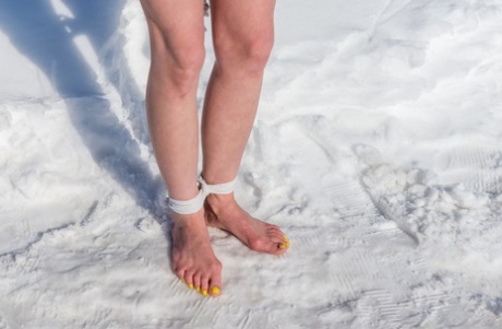 金发碧眼的女孩克劳迪娅跪在白雪复盖的地面，而在红色的便服绑定