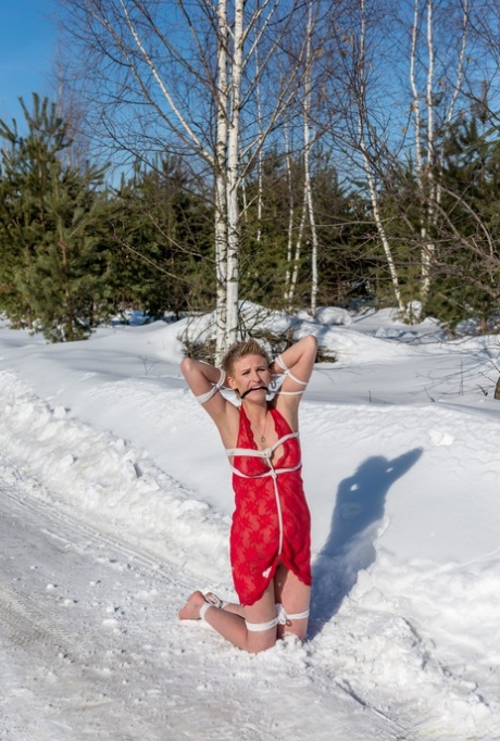 金发碧眼的女孩克劳迪娅跪在白雪复盖的地面，而在红色的便服绑定