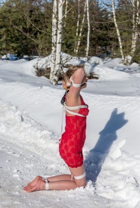 金发碧眼的女孩克劳迪娅跪在白雪复盖的地面，而在红色的便服绑定