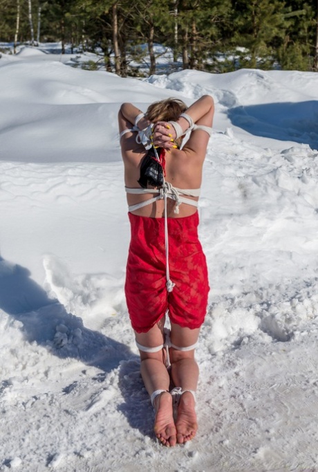 金发碧眼的女孩克劳迪娅跪在白雪复盖的地面，而在红色的便服绑定