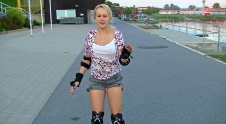 Roller skating blonde girl pauses alongside a roadway to jerk off a dick