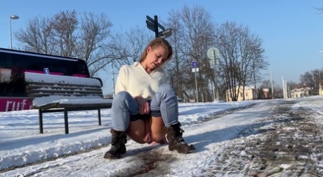 白人女孩朱丽娅白天在白雪覆盖的小路上小便