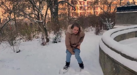 漂亮女孩朱莉娅在公园里脱下裤子在积雪覆盖的地面上撒尿