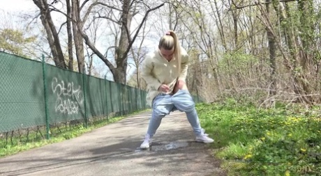 Blonde girl Bianca pulls down sweatpants to pee on a paved walking path