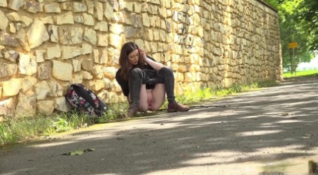 Pretty girl Aleya pulls down her pants to piss on a paved roadway