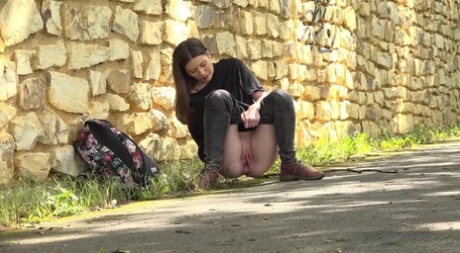 Pretty girl Aleya pulls down her pants to piss on a paved roadway