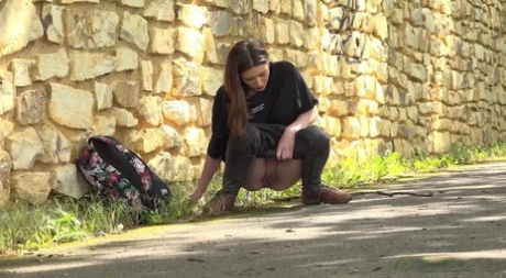 Pretty girl Aleya pulls down her pants to piss on a paved roadway