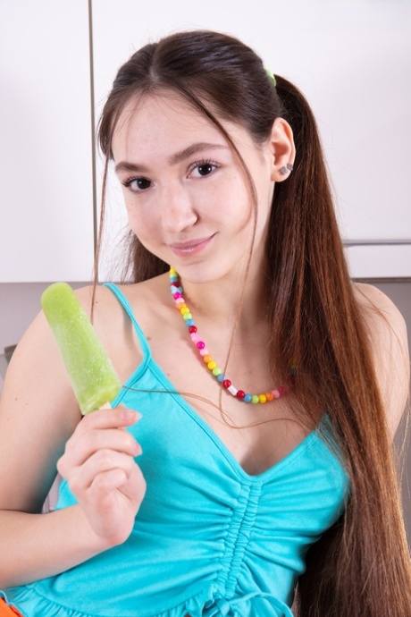 Charming teen Fendi eats a popsicle while getting bare naked in the kitchen