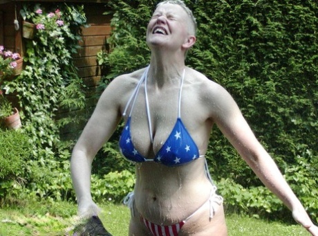 Mature woman Tiffany Pearl soaks herself with a hose while taking off a bikini