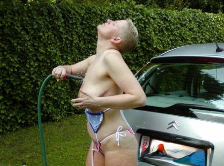 Mature woman Tiffany Pearl soaks herself with a hose while taking off a bikini