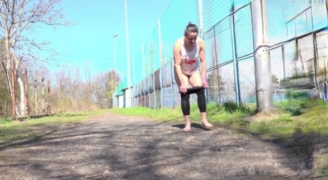 Caucasian woman Valentina Ross pulls down her leggings to piss on a path