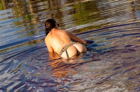 Brunette MILF goes nude at a waterhole while fitted with a tail butt plug