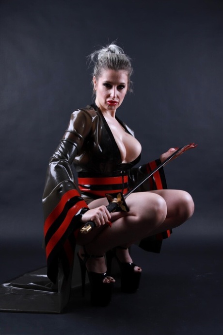 Platinum blonde solo model wields a sword while outfitted in a latex costume