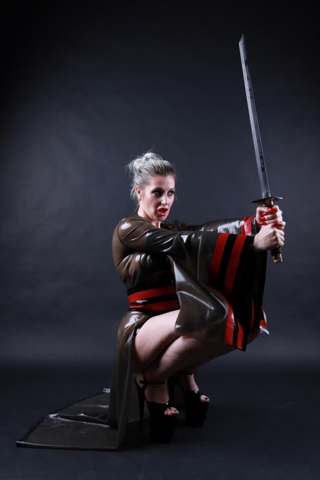 Platinum blonde solo model wields a sword while outfitted in a latex costume